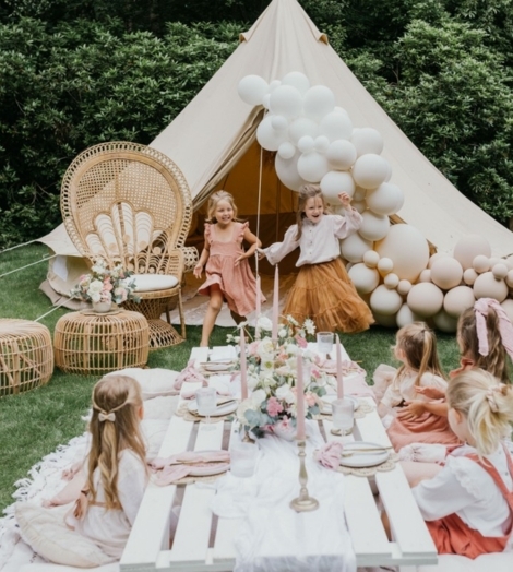 Kinderen aan feesttafel met bloemen en kaarsjes
